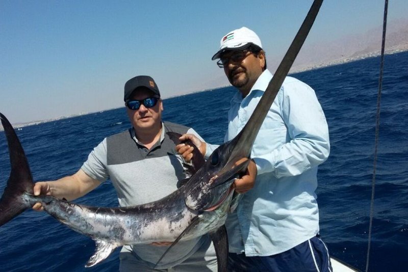Proud fishermen holding their catch during deep sea fishing in Aqaba Proud fishermen holding their catch during deep sea fishing in Aqaba